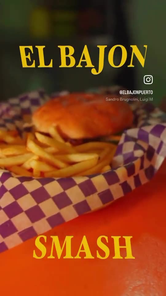 Canasta de El Bajón con burger y papas sobre la barra naranja.