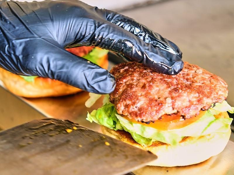 Mano con guante negro sirviendo la carne con una espátula.