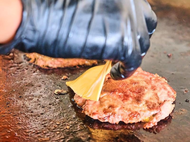 Rebanada de queso americano puesta sobre la carne en la plancha.