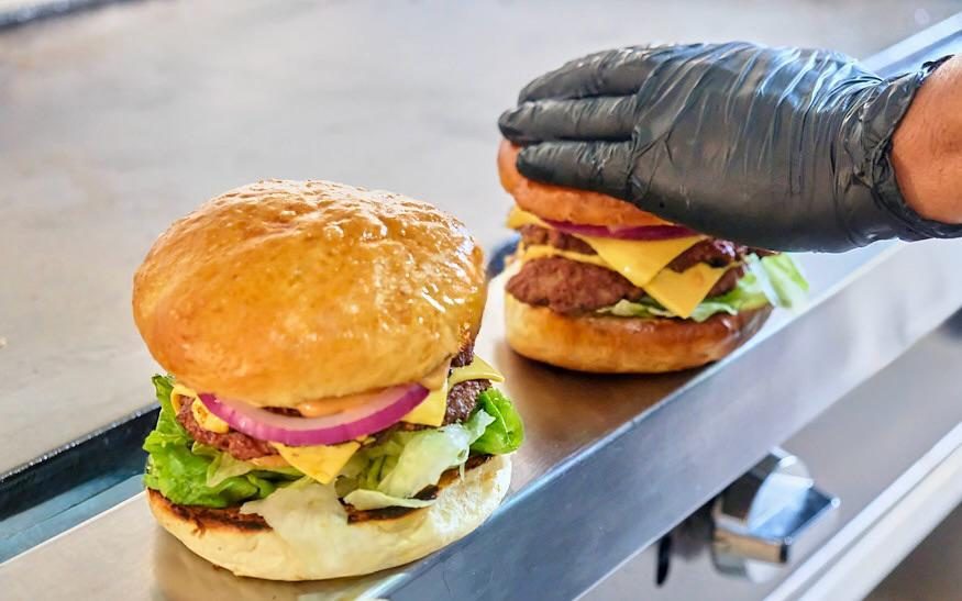 Burger con queso y cebolla morada sobre la plancha.